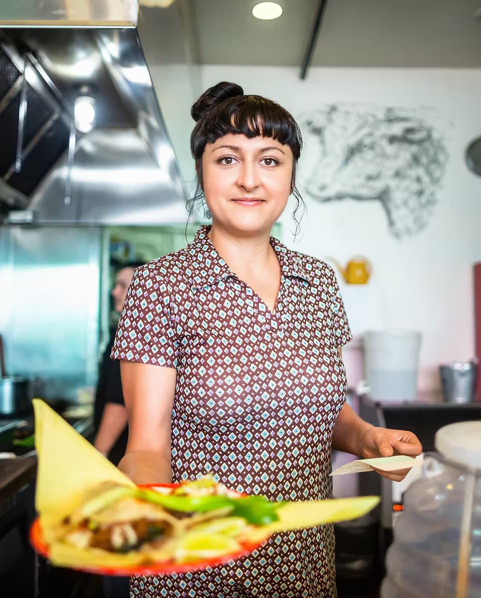 Roberta's Cocina Mexicana server proudly holding a plate of tacos in the restaurant kitchen, Sacramento CA